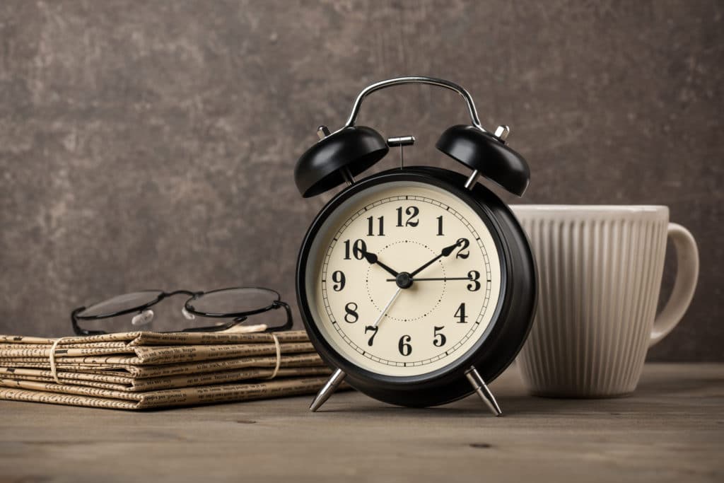 Newspapers, Glasses, Alarm Clock And Coffee Cup On Desktop